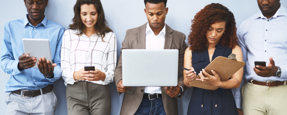 Group of healthcare professionals checking laptops, tablets and phones to stay on top of industry trends and news